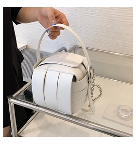 Detailed view of a white woven PU leather box bag with silver chain and top handle