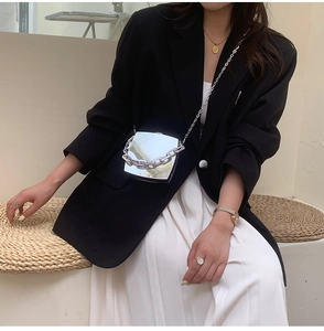 Silver mirror mini box bag with chunky chain strap worn by model in minimalist outfit