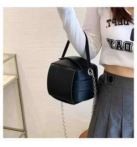 Detail view of the black geometric puzzle box bag with silver metal chain and top handle