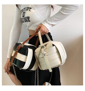 Detail view of woven leather cylinder bags in black-white and cream colors with chain straps