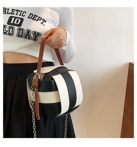 Detail of checkered black and white box bag with brown handle and silver chain strap