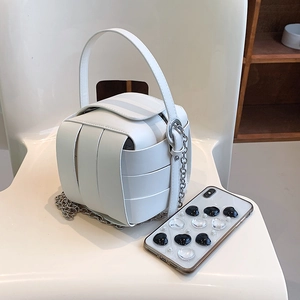 Fashionable white quilted box bag with chunky silver chain on minimalist chair