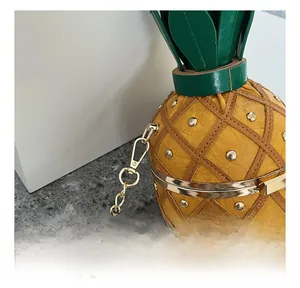 Close-up of golden metal hooks and chain on the yellow pineapple-shaped bag