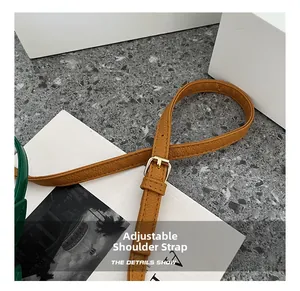 Detail of adjustable brown lychee grain leather shoulder strap with gold metal buckle