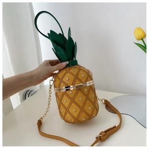 Close-up of creative pineapple cross-body bag with golden studs and green leather leaves
