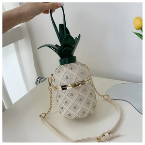 Detail of pineapple-shaped crossbody bag with gold studs and green leaf top handle