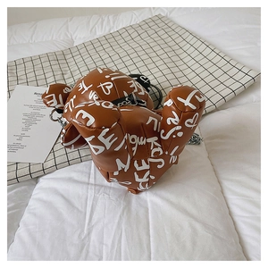 Detail of bear-shaped brown leather crossbody bag with white graffiti and chain strap