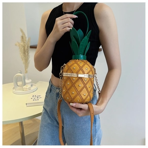 Detail of pineapple bag with gold rivets, green leaf handle and chain strap
