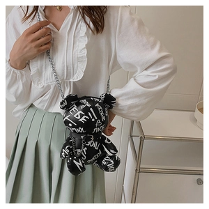 Detail of bear-shaped crossbody bag featuring white Russian graffiti and silver chain strap