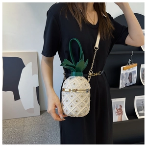 Detail of pineapple-shaped crossbody bag featuring woven texture and gold studs