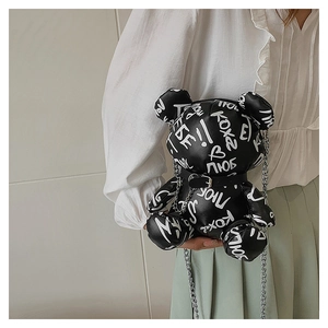 Close-up of black bear-shaped chain bag with white graffiti and silver metal hardware