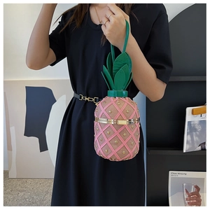 Close-up of pink pineapple-shaped clutch bag with gold studs and green leaf handle