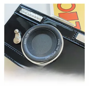 Macro detail of glossy black patent camera bag showing lens design and spotlight text