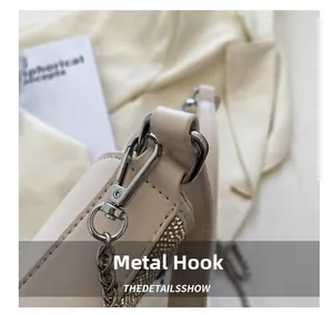 Gros plan du fermoir en métal poli et des strass argentés sur un sac à main beige clair