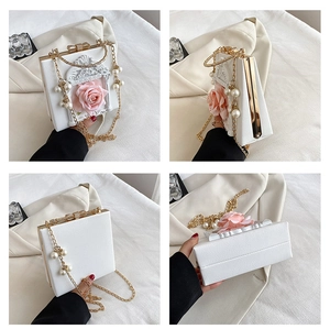 Detail view of white rigid box bag with pink 3D rose and gold chain with pearls