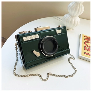 Detailed close-up of dark green patent leather camera bag with silver chain strap
