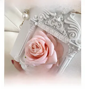 Close-up of white PU leather box bag with pink rose flower and pearl chain strap