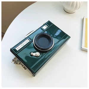Detail of dark green patent leather camera bag with metallic chain and spotlight text
