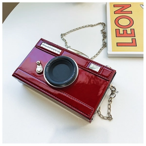 Macro shot of camera-shaped crossbody bag in burgundy patent leather and silver chain
