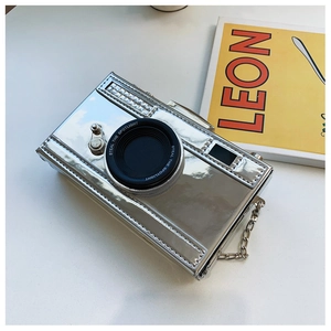 Close-up of a silver camera-shaped crossbody bag with glossy finish and chain strap