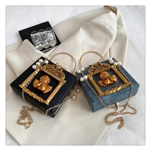 Macro shot of luxury square box bags with gold angel reliefs and pearl chain straps