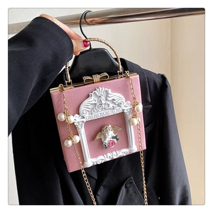 Detail of pink box bag featuring baroque angel relief, bow clasp, and pearl chain handle