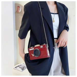 Detail view of burgundy patent leather camera-shaped crossbody bag with silver chain strap