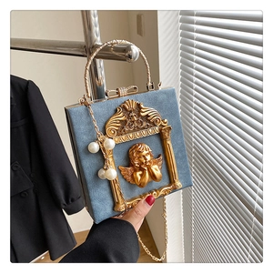 Detailed macro view of the blue velvet box bag featuring a golden cupid relief and pearl chain