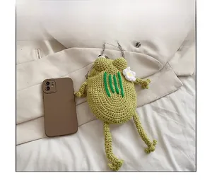 Detail view of a green crochet frog crossbody bag with floral accents and metal chain