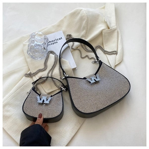 Détail de sacs hobo en strass avec logo W argenté et bandoulière chaîne sur blazer