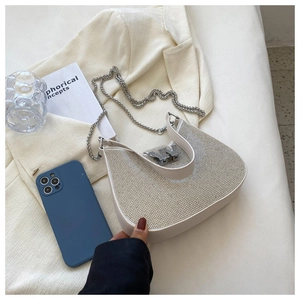 Détail du sac baguette en strass blanc avec chaîne argentée et boucle en métal