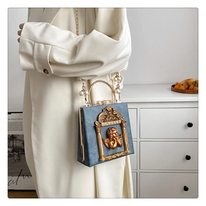 Detail of blue box bag with gold angel relief and pearl chain on a stylish model