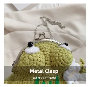 Detail shot of green crochet frog purse with metal kiss-lock closure and white flower