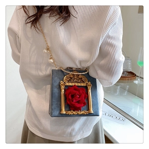 Detail of blue velvet box bag with a 3D red rose and golden baroque frame