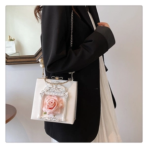 Detail of white leather box bag featuring a 3D pink rose and elegant pearl chain