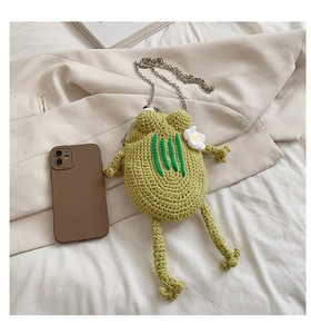 Detailed shot of green knitted frog crossbody bag with floral accents and chain strap