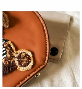Detalle macro del bolso de cuero marrón con bordado de tigre y cremallera metálica