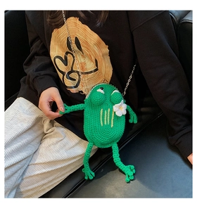 Detail of a handmade green frog crochet bag with metal clasp and gold chain strap