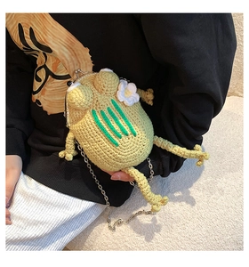 Close-up of handmade green knitted frog crossbody bag with metal clasp and chain strap