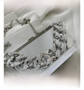 Detail view of silver acrylic box bag with thick chain handle on white silk background