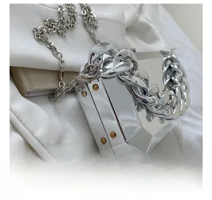 Detail of silver mirror metal box bag featuring chunky chain handle and side rivets