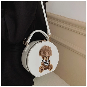 Detailansicht der weißen runden Bärentasche, getragen zu einem schwarzen Sakko