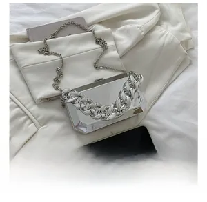 Detail shot of the silver mirror box bag showing compact size compared to a phone