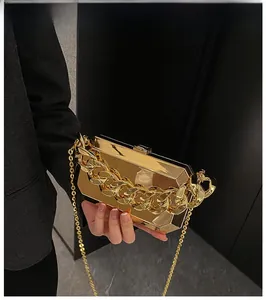 Detail of mirror gold geometric evening box clutch with chunky chain and sleek metal strap