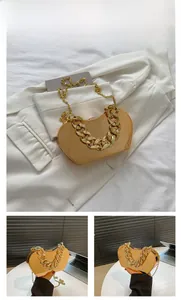 Detail view of heart-shaped gold clutch with chunky chain strap and metallic finish