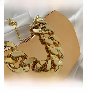 Close-up of high-quality chunky gold metal chain strap on a designer box clutch