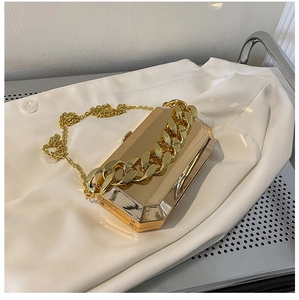 Close-up of golden octagonal metal clutch with mirror finish and bold chain detail