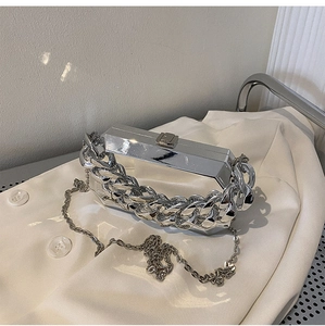 Close-up of a silver mirror acrylic box bag with chunky chain detail and thin strap