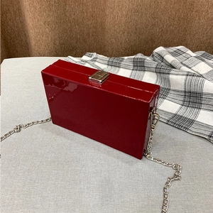 Macro detail of wine red hardshell purse with glossy finish and silver chain strap