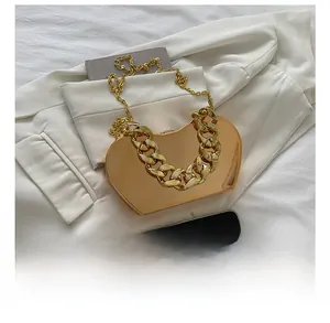 Macro shot of gold heart-shaped metal clutch bag with luxury chain and mirror finish